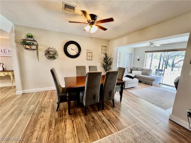 dining area featuring ceiling fan, a textured ceiling, and light wood-type flooring