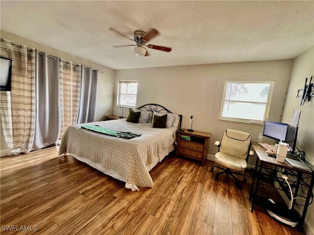 bedroom with hardwood / wood-style flooring, ceiling fan, and a textured ceiling