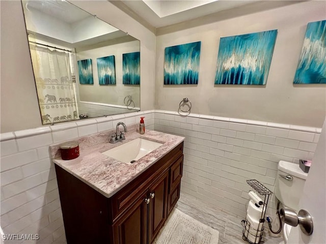 bathroom with tile walls, vanity, and toilet