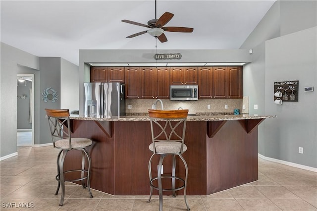 kitchen featuring stainless steel appliances, a kitchen island with sink, a kitchen breakfast bar, and decorative backsplash