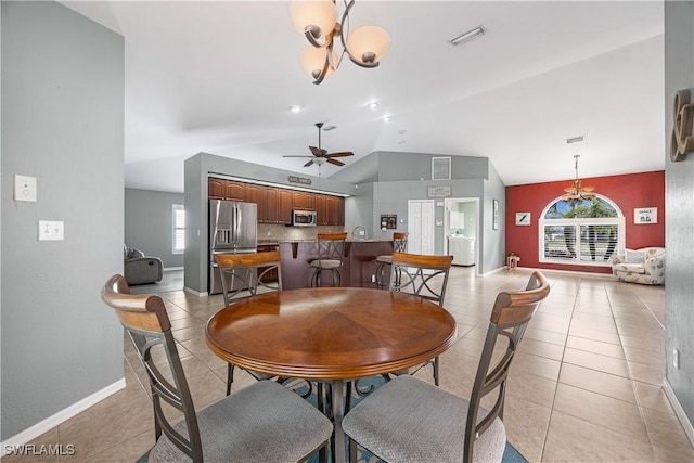 dining room with light tile patterned floors, ceiling fan with notable chandelier, and vaulted ceiling