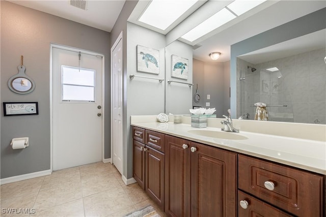 bathroom featuring vanity, a skylight, tile patterned floors, and tiled shower