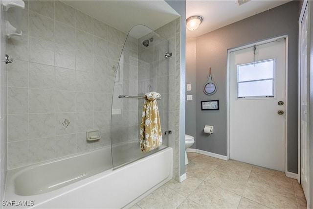 bathroom featuring tiled shower / bath combo, tile patterned floors, and toilet