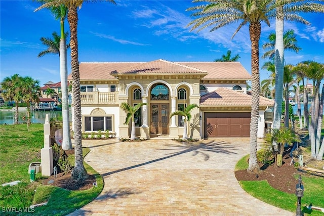 mediterranean / spanish-style house featuring a tiled roof, french doors, decorative driveway, and an attached garage