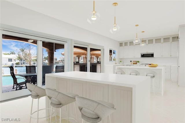 342 Germain Ave, Naples, FL 34108 - kitchen with stainless steel microwave, light tile patterned floors, glass insert cabinets, a breakfast bar area, and a kitchen island