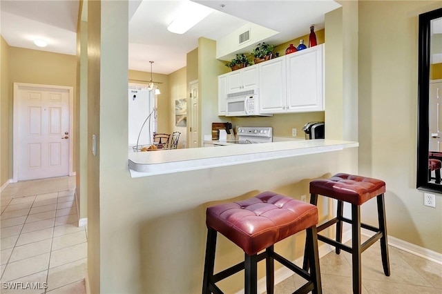 kitchen with a breakfast bar, kitchen peninsula, pendant lighting, white appliances, and white cabinets