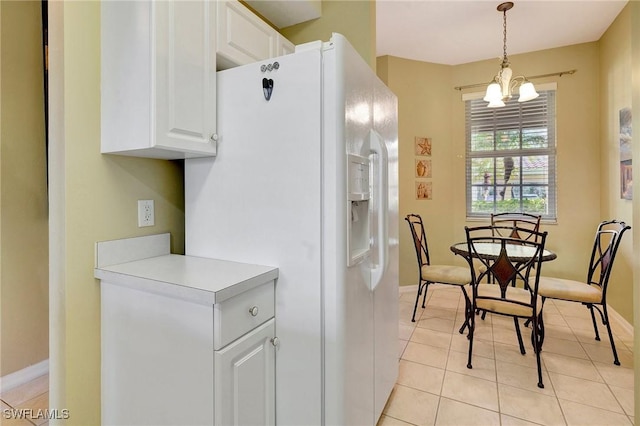 kitchen with decorative light fixtures, a chandelier, light tile patterned floors, white refrigerator with ice dispenser, and white cabinets