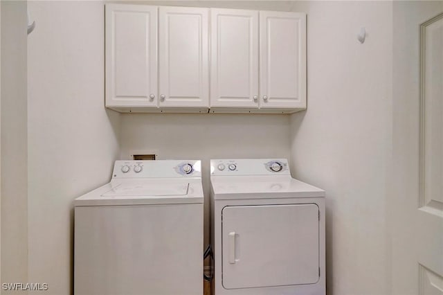 clothes washing area with cabinets and separate washer and dryer