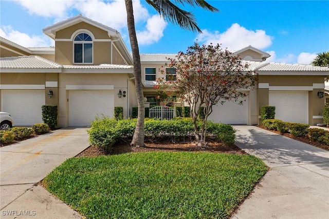 multi unit property with a tile roof, driveway, and stucco siding