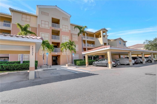 view of property featuring covered and uncovered parking