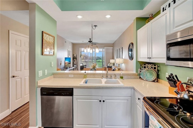 kitchen with white cabinets, open floor plan, stainless steel appliances, light countertops, and a sink