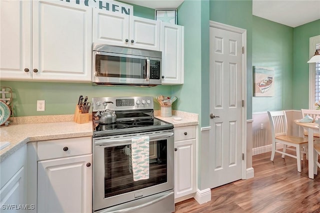 kitchen featuring stainless steel appliances, baseboards, white cabinets, light countertops, and light wood-type flooring