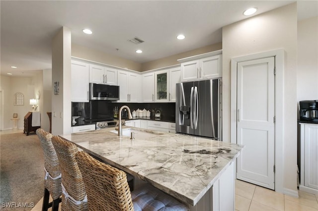 kitchen featuring white cabinetry, light stone countertops, backsplash, and stainless steel appliances