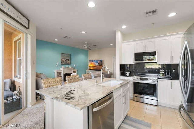 kitchen featuring a breakfast bar, sink, white cabinets, a kitchen island with sink, and stainless steel appliances