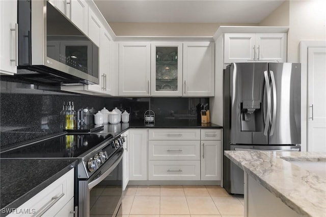 kitchen featuring white cabinetry, stainless steel appliances, and dark stone countertops