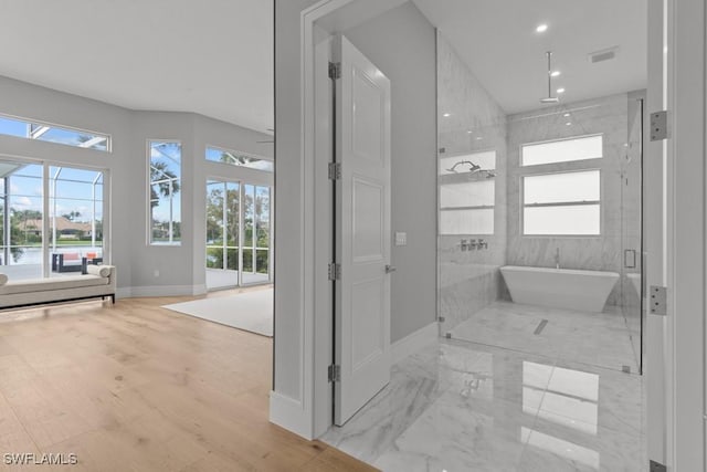 bathroom featuring wood-type flooring, separate shower and tub, and a healthy amount of sunlight