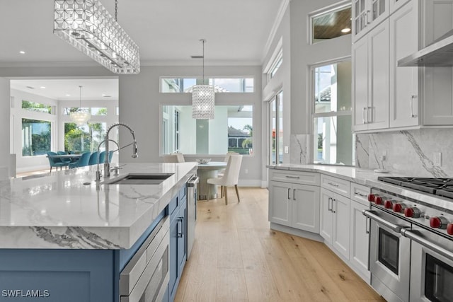4306 Sanctuary Way, Bonita Springs, FL 34134 - kitchen with range with two ovens, a sink, ornamental molding, wall chimney range hood, and an inviting chandelier