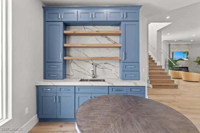 bar featuring sink, light hardwood / wood-style flooring, light stone counters, and decorative backsplash