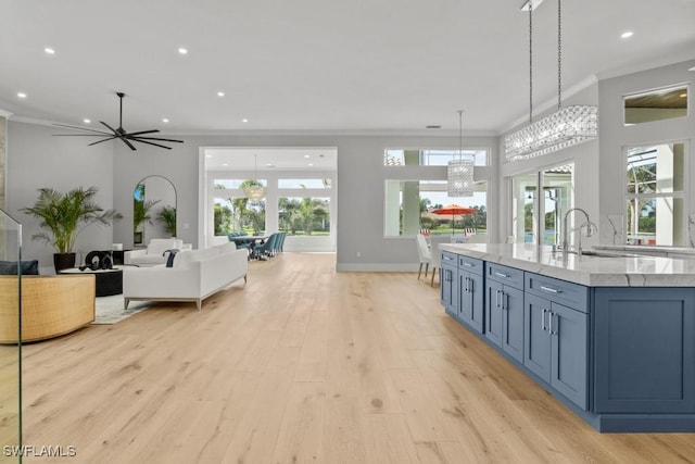 4306 Sanctuary Way, Bonita Springs, FL 34134 - kitchen with decorative light fixtures, light wood finished floors, ornamental molding, a sink, and light stone countertops