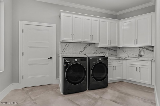 clothes washing area featuring washer and dryer, sink, crown molding, and cabinets