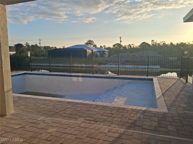 pool at dusk featuring a patio area