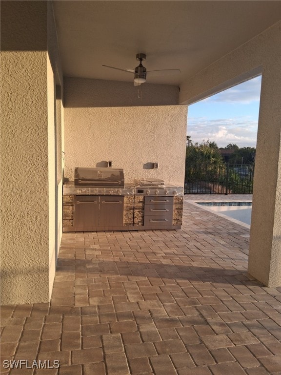 view of patio featuring a grill, a fenced in pool, ceiling fan, and exterior kitchen