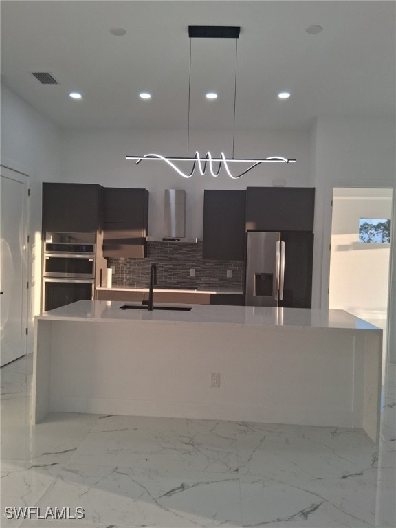 kitchen featuring appliances with stainless steel finishes, decorative light fixtures, sink, backsplash, and wall chimney exhaust hood