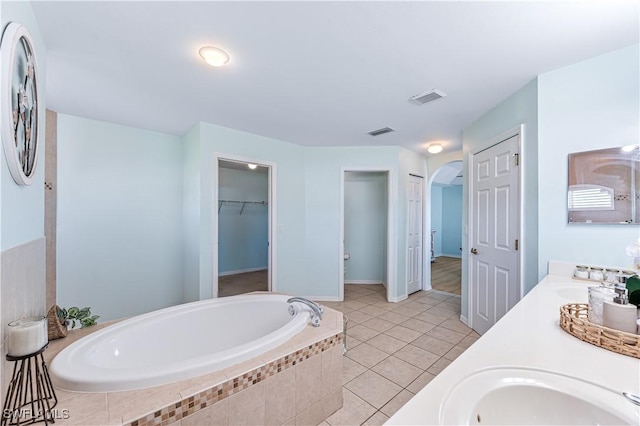 bathroom with tiled tub, vanity, and tile patterned floors