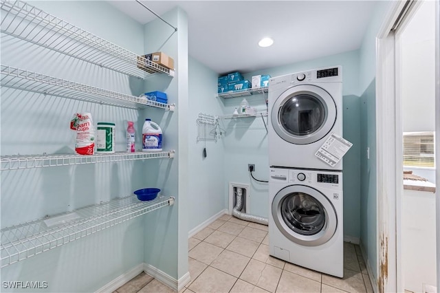 clothes washing area featuring stacked washing maching and dryer and light tile patterned floors