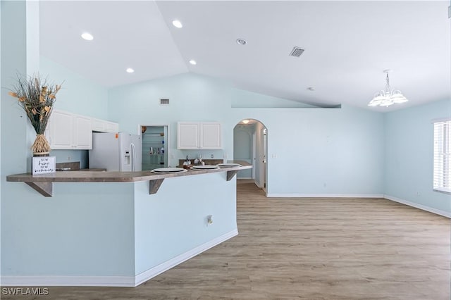 kitchen with a kitchen bar, white cabinetry, decorative light fixtures, kitchen peninsula, and white refrigerator with ice dispenser