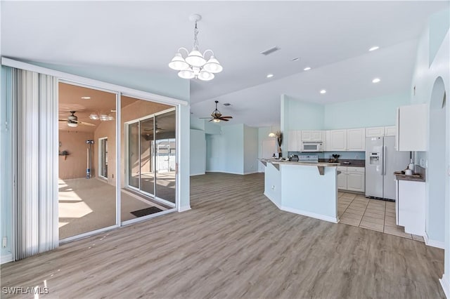 kitchen featuring pendant lighting, ceiling fan with notable chandelier, white cabinetry, white appliances, and light hardwood / wood-style flooring