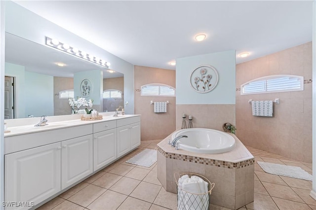 bathroom featuring vanity, a relaxing tiled tub, and tile patterned floors