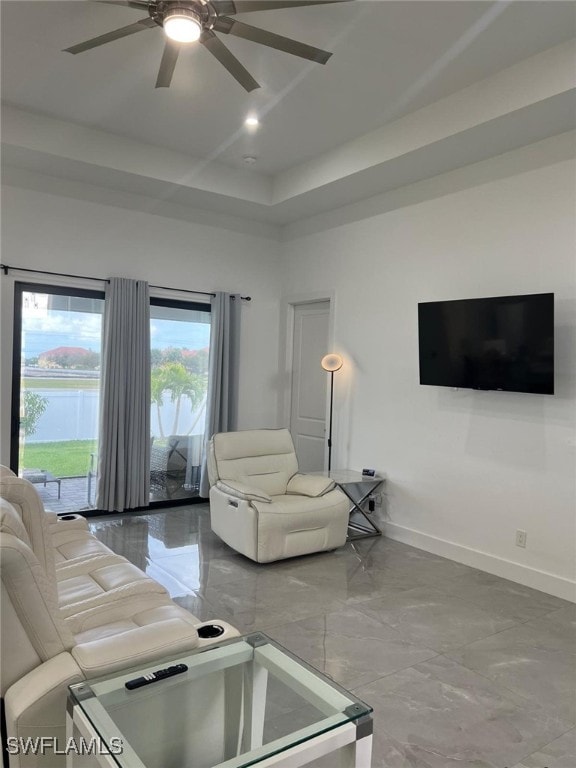 living room featuring ceiling fan and a tray ceiling