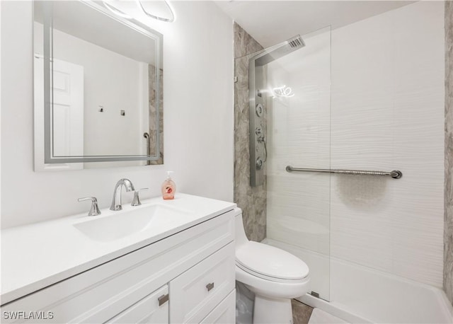 bathroom with a tile shower, vanity, and toilet