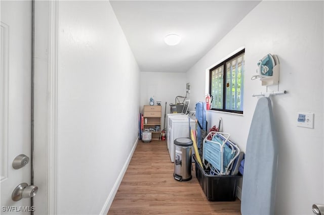 hallway with light wood-type flooring, washer / dryer, and baseboards