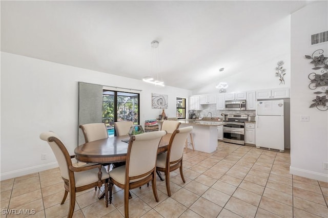 dining area featuring visible vents, vaulted ceiling, baseboards, and light tile patterned floors