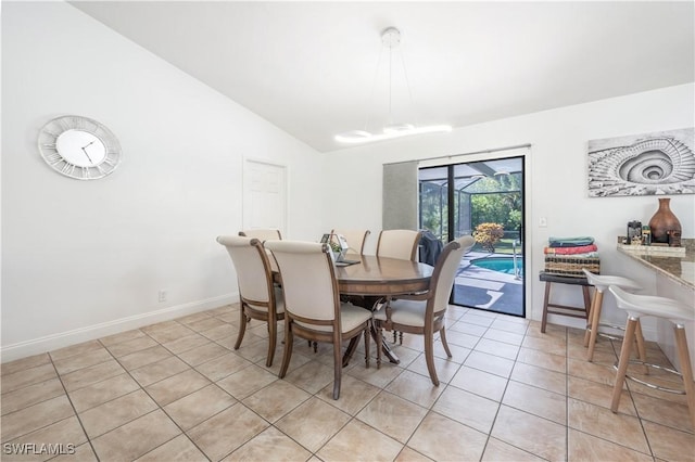 dining space featuring light tile patterned flooring, vaulted ceiling, and baseboards