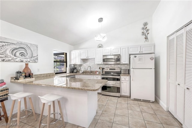 kitchen with a peninsula, appliances with stainless steel finishes, a sink, and white cabinetry