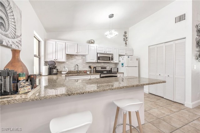 kitchen with a peninsula, appliances with stainless steel finishes, pendant lighting, and white cabinets