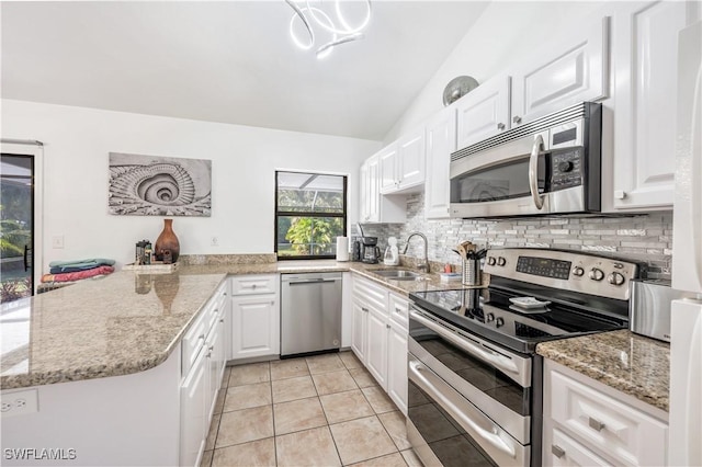 kitchen with stainless steel appliances, decorative backsplash, white cabinets, a sink, and a peninsula