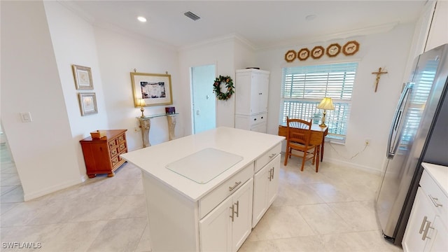 6082 National Blvd Unit 128, Ave Maria, FL 34142 - kitchen featuring white cabinets, ornamental molding, stainless steel refrigerator, and an island with sink