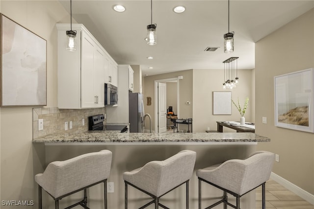 kitchen with pendant lighting, stainless steel appliances, and white cabinets