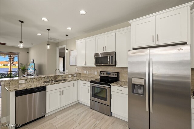 kitchen featuring appliances with stainless steel finishes, white cabinetry, sink, hanging light fixtures, and kitchen peninsula