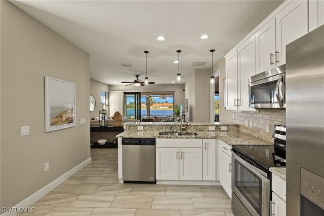 kitchen featuring sink, kitchen peninsula, pendant lighting, stainless steel appliances, and white cabinets