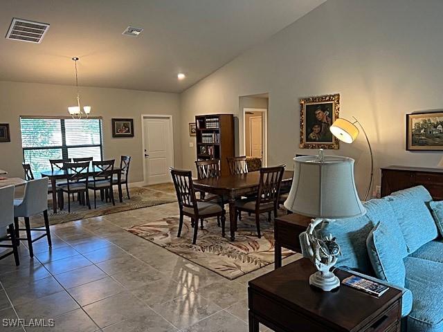 tiled living room featuring a chandelier and high vaulted ceiling