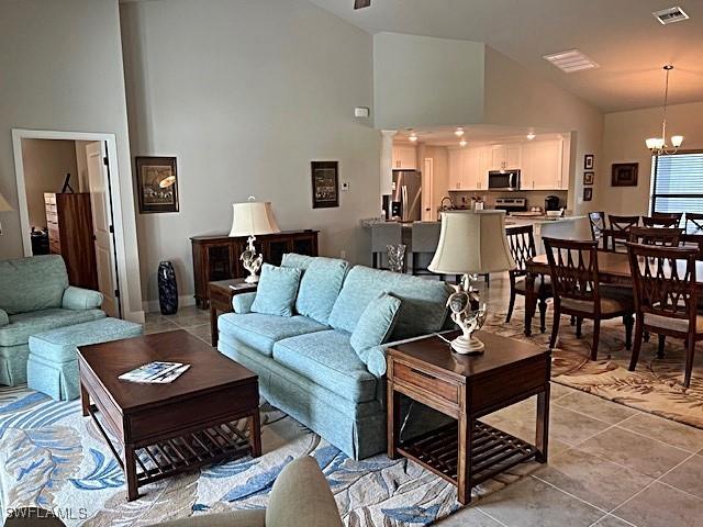 living room with light tile patterned floors, high vaulted ceiling, and a chandelier