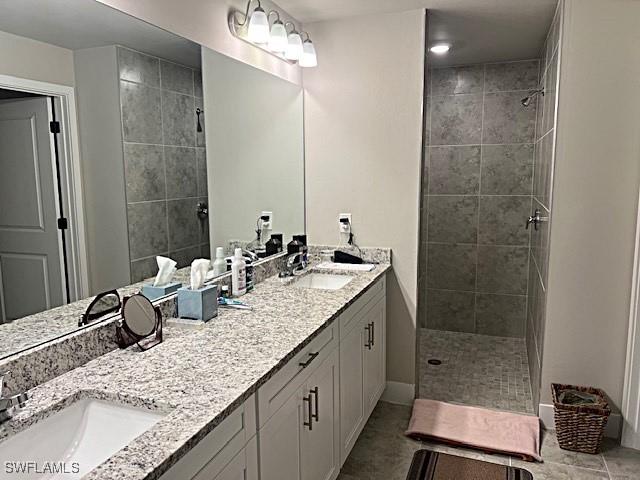 bathroom with tile patterned floors, vanity, and a tile shower