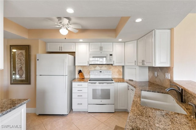 kitchen with white cabinetry, light stone countertops, sink, and white appliances