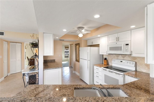 kitchen with sink, white cabinetry, a tray ceiling, stone counters, and white appliances