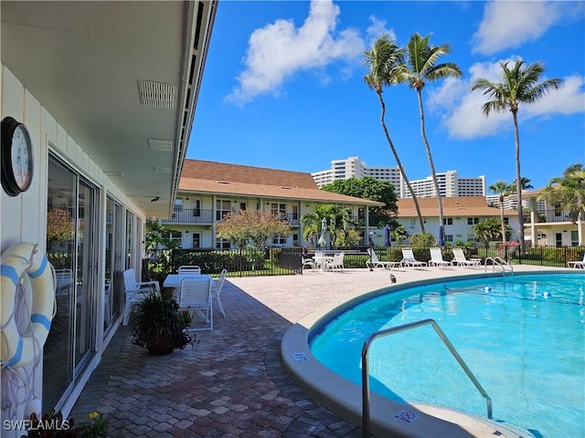 community pool with a patio area and fence